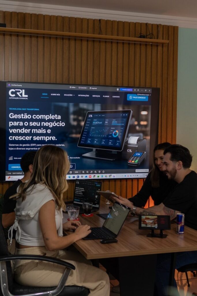 Colleagues collaborating around a table with a large screen display.